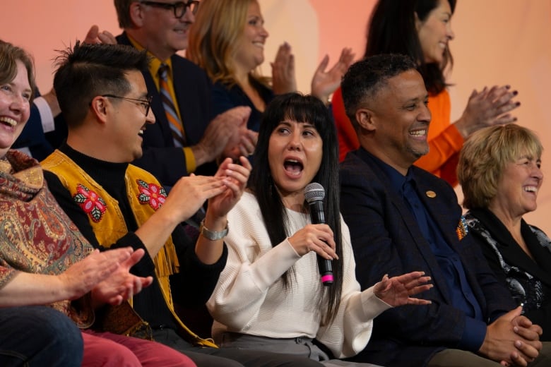 Several people sit on stage and talk.