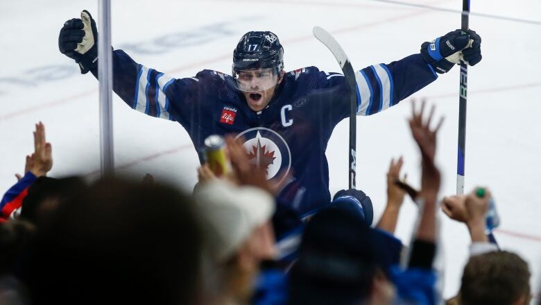 Winnipeg Jets' Adam Lowry raises both his hands in the air as the crowd cheers inside Canada Life Centre in Winnipeg on Saturday, Oct. 14, 2023.