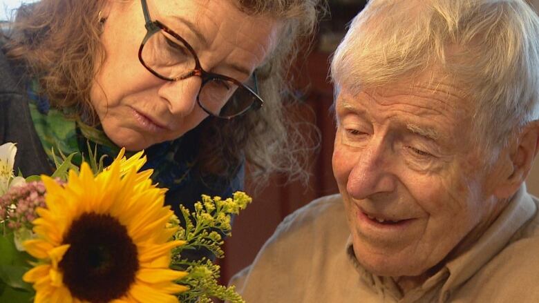 A woman and a man look at a sunflower. 