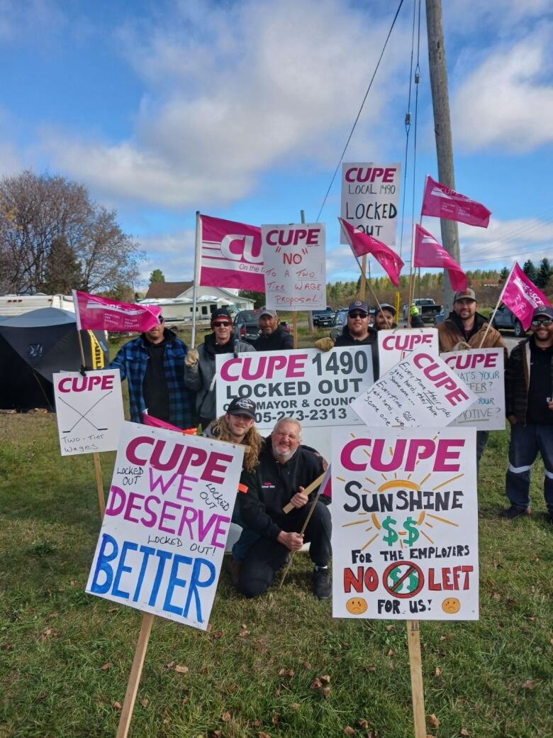 People on a picket line holding colourful signs.