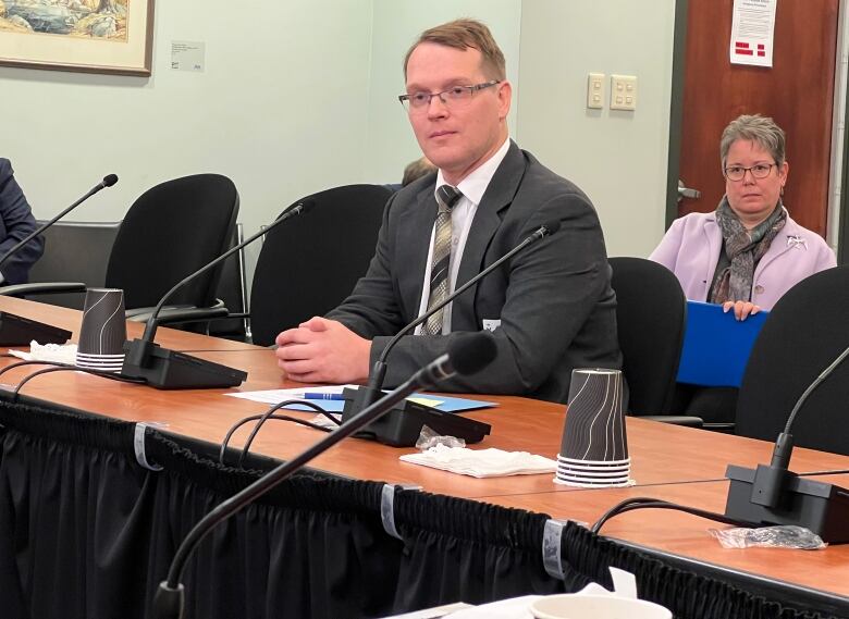 A man with glasses sits at a table.