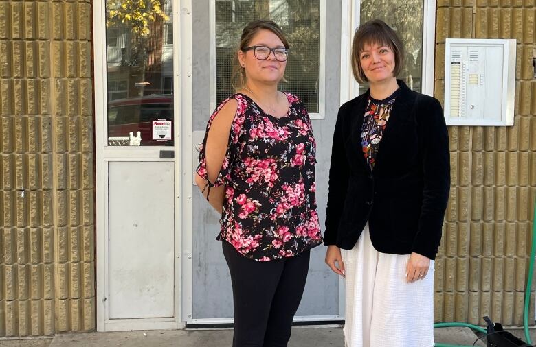 Two women stand in front of a condo complex