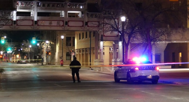 A police officer stands in a taped-off section of a street.