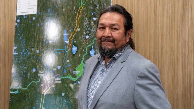 A man stands in front of a poster of a map.