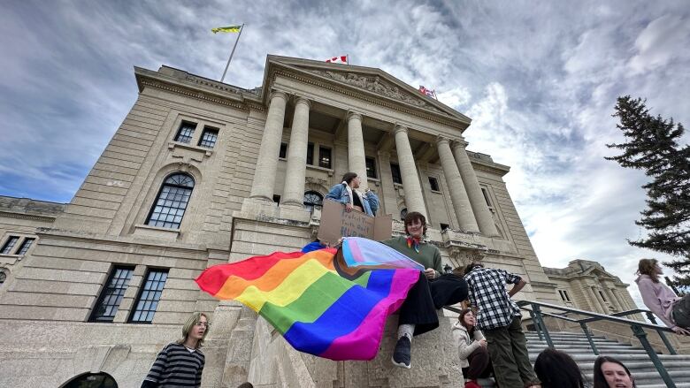 A youth waves a LGBTQ2+ flag on the steps of the provincial legislature in Regina, Sask. 