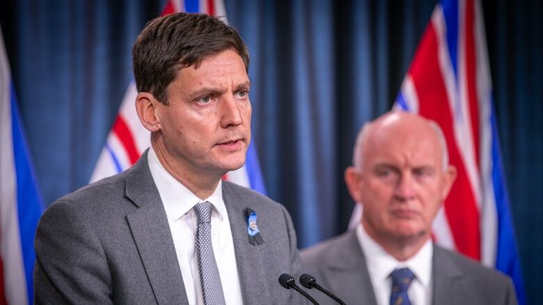 Two white men in suits deliver press conference.