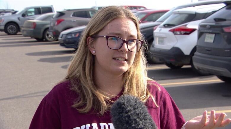 A spectacled blonde woman in a red hoodie.