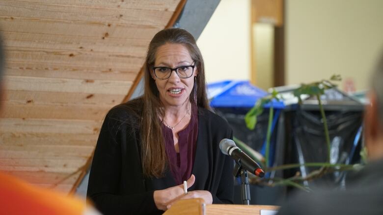 A woman is wearing a black dress and speaking in public.