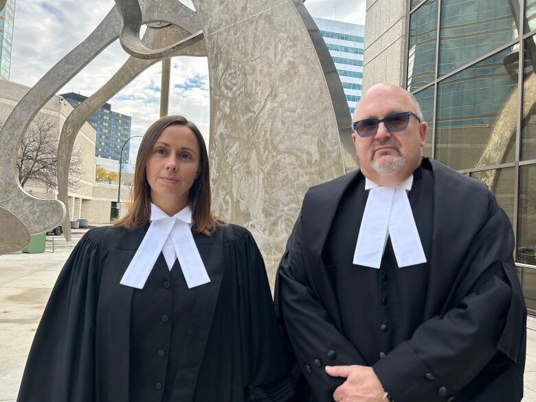 Two lawyers stand outside a law courts building.