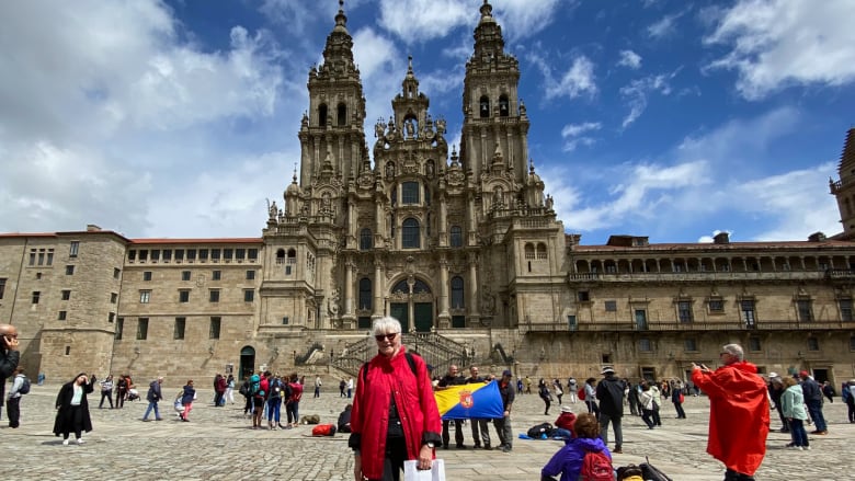 A woman stands in front of an old cathedral.