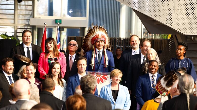 A man in a suit and headdress surrounded by people in suits and dresses.