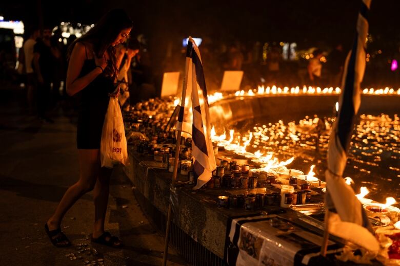 A woman stands in front of lighted candles