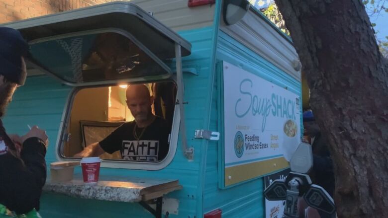 Bobby Reaume serves soup and a coffee to someone at Windsor's Soup Shack trailer.