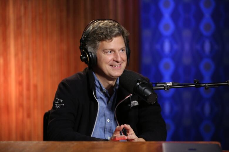 Head shot of James Ehnes smiling, wearing headphones and sitting in front of a studio microphone.