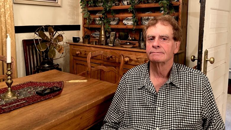 A 76-year-old man sits at his dining room table, in front of part of his antique collection.