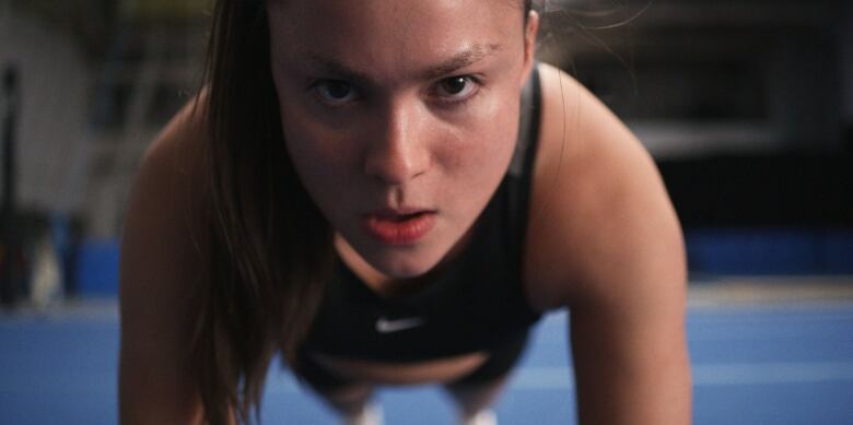 Close up on a woman's face as she does pushups.