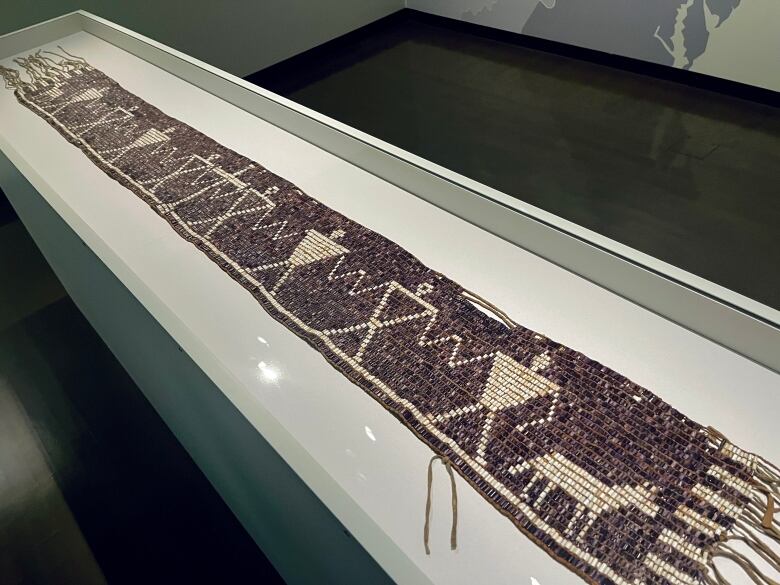 A wampum belt in a glass case.