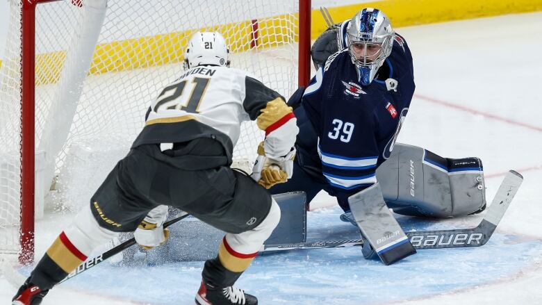 A hockey player scores into a net as the goalie stretches across in an attempt to make a save.