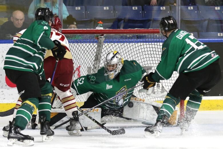 Hockey players skate around goaltender near net. The Cape Breton Eagles and Acadia Bathurst Titan play in the QMJHL.