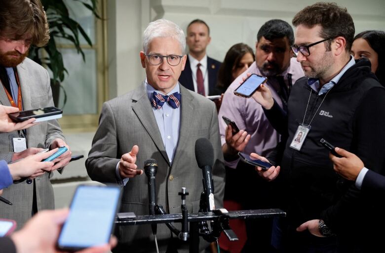 Reporters around man in bowtie