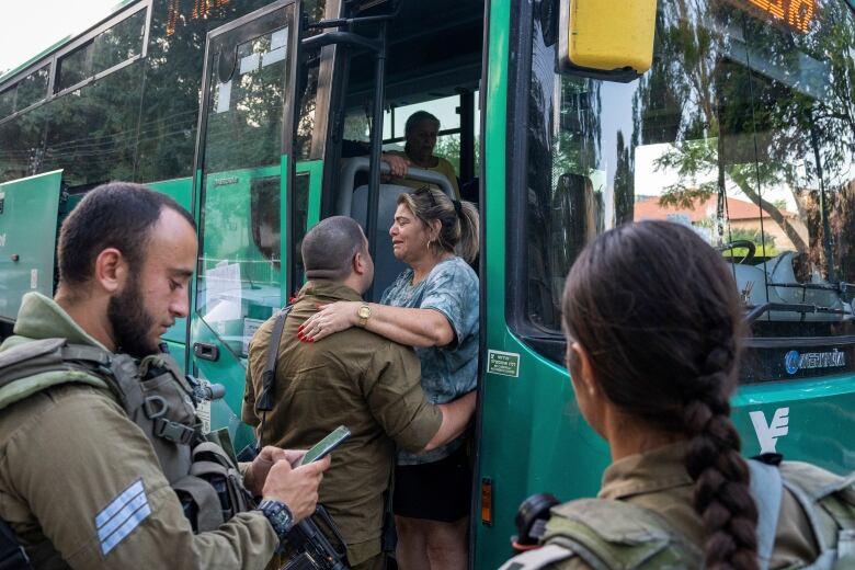 Israeli soldiers help a woman as she gets on a bus to evacuate from the northern Israeli city of Kiryat Shmona, Israel.