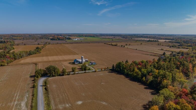 Farm land in the fall shown from above. A silver farm house. 