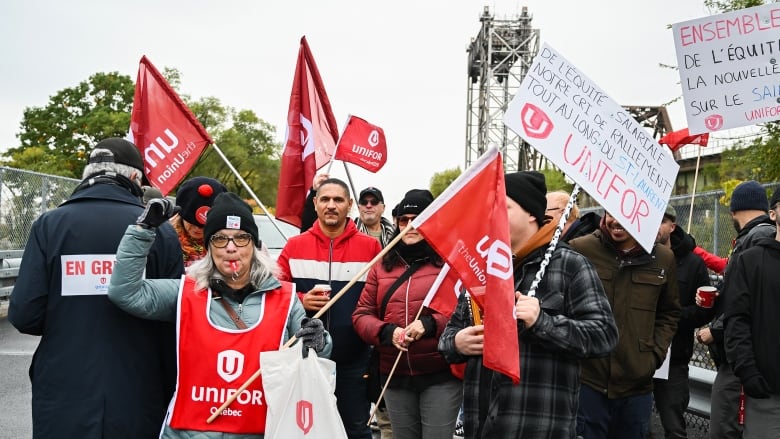 people wave union flags, and blowing whistles outside port infrastructure