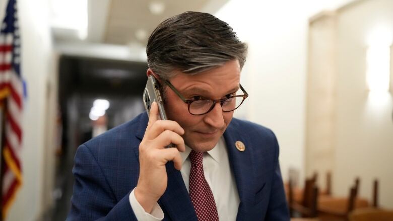 A politician holds a cell phone up to their ear.