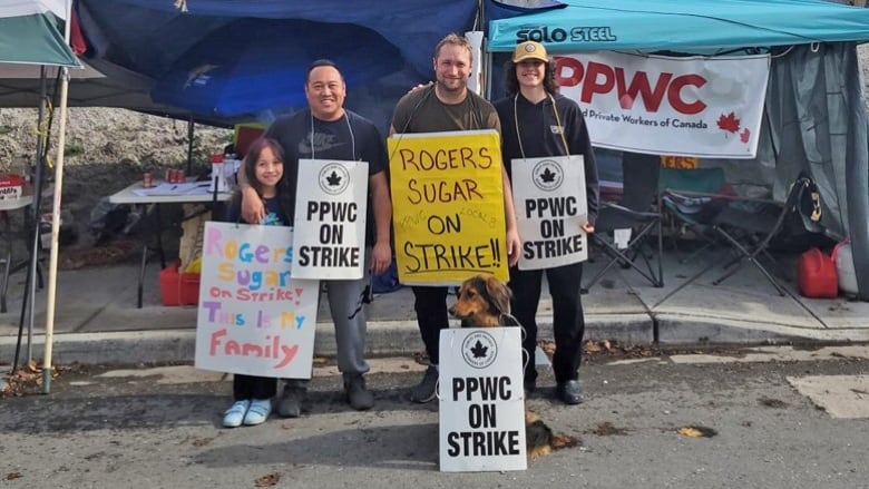 Three Rogers sugar employees with a child and a dog holding up strike signs