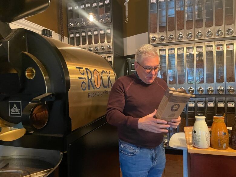 A man holding a bag of coffee in a coffee shop.