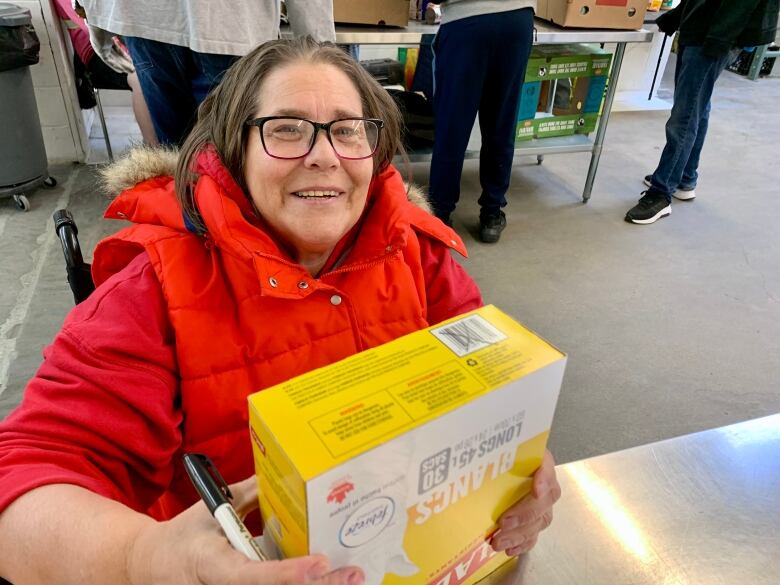 A woman in a wheelchair with glasses and a red jacket. 