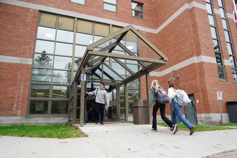 students walk into a building wearing backpacks