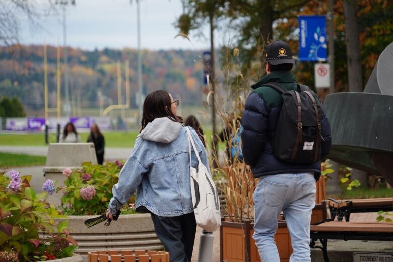 Two adult students walk on a school campus