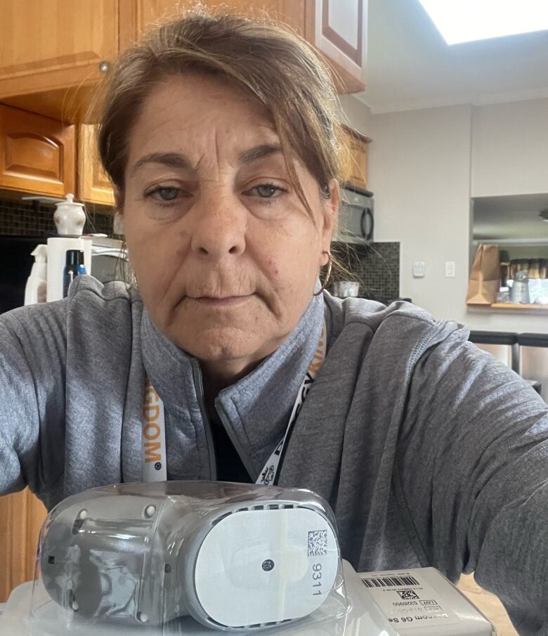 A woman sits at a table with medical equipment in front of her.