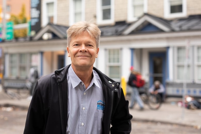 A man poses in front of a housing and social support centre.