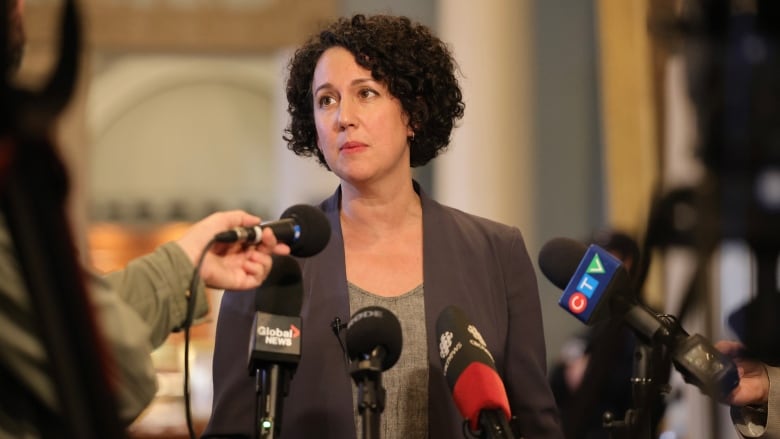 A woman is surrounded by microphones.