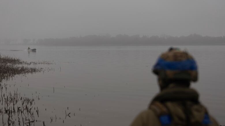 A Ukrainian soldier observes a colleague sailing along the Dnipro river near Kherson, Ukraine.