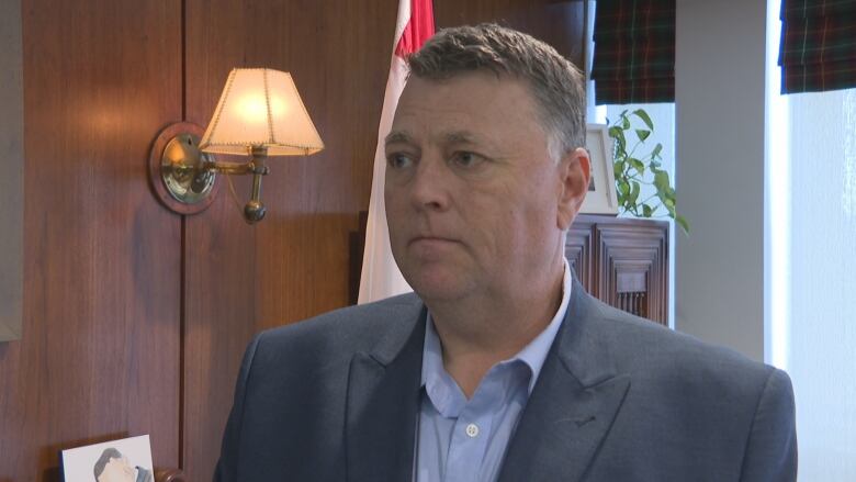 Man in a business jacket and blue open-necked shift in an office.