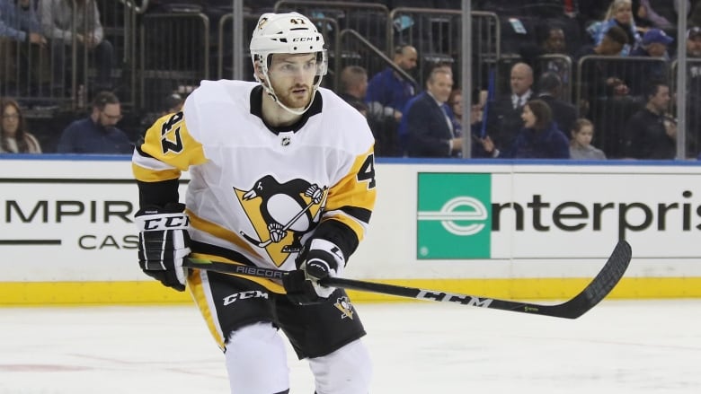 A hockey player wearing a yellow, white, and black jersey is shown during a game.