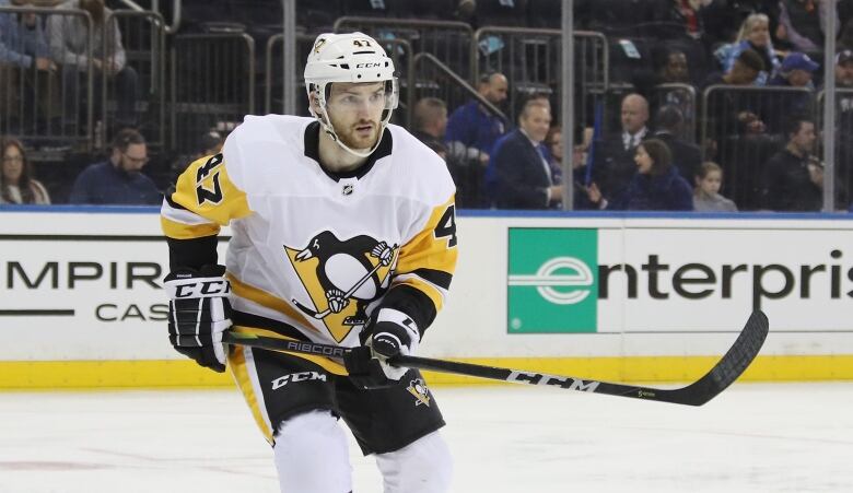 A hockey player wearing a yellow, white, and black jersey is shown during a game.