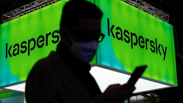 A man stands in front of a sign advertising Kaspersky. 