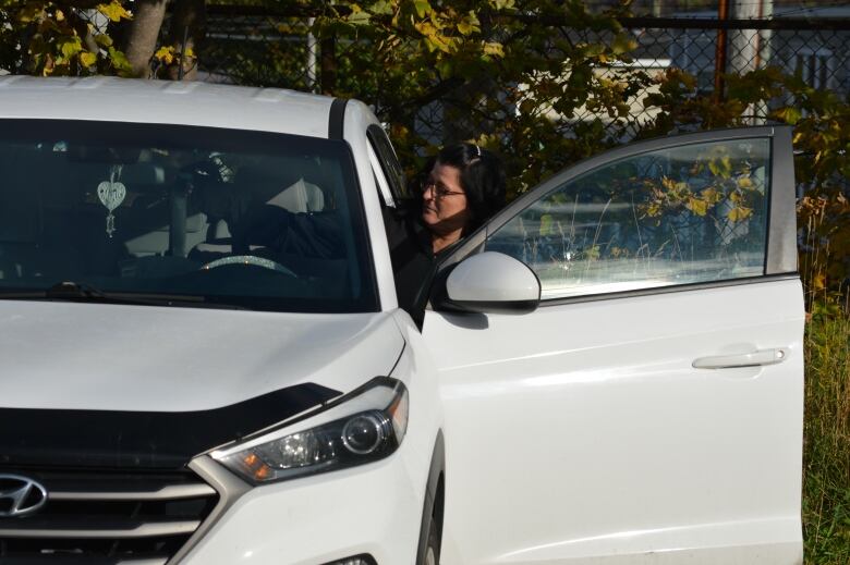 A woman gets into a white car