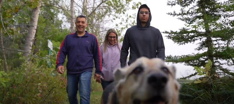 Lucas Oanta and his parents go for a walk with their dog in Saskatoon.