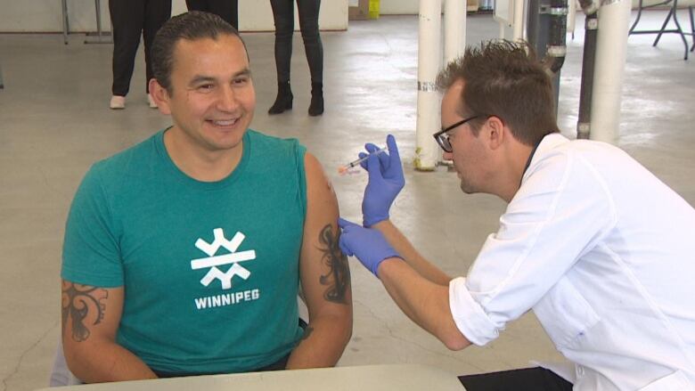 A man is shown receiving a vaccine.