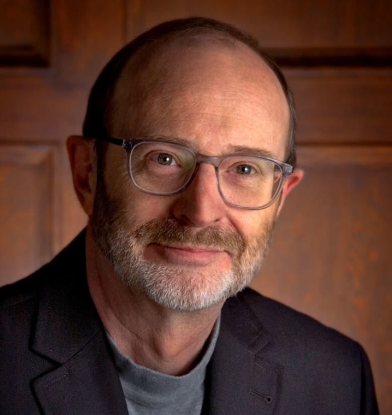 A middle-aged man with a beard, wearing glasses and a suit, sits in a wood-paneled office at the Newfoundland and Labrador Medical Association.