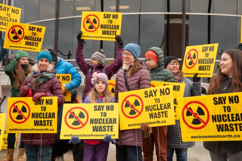 A group of people hold yellow signs.