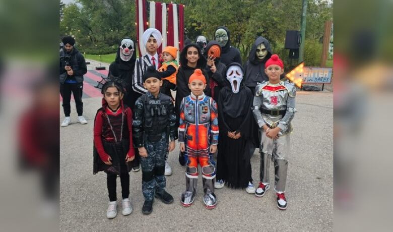 Children wearing Halloween costumes stand together for a picture.