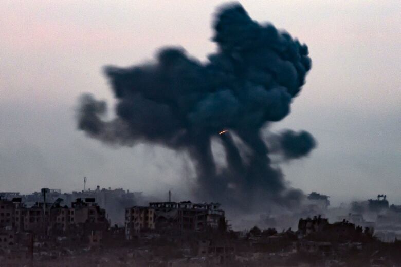 Smoke rises above a destroyed city.