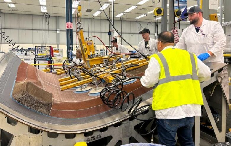 Manufacturing workers surround a landing gear door.