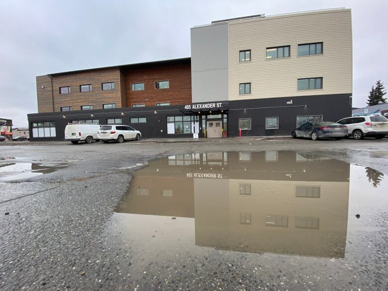 A 3-storey building is seen from across a parking lot. 